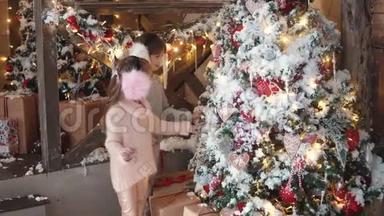 圣诞节或新年。 孩子们迷人地看着新年树。 有毛的小女孩把圣诞玩具挂在耳朵上